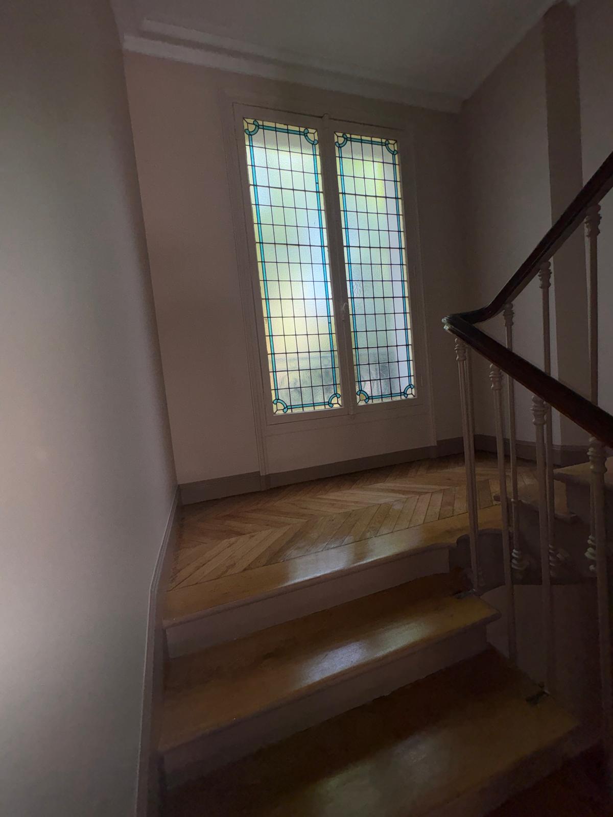 Palier de cage d'escalier après rénovation avec vitrail et parquet