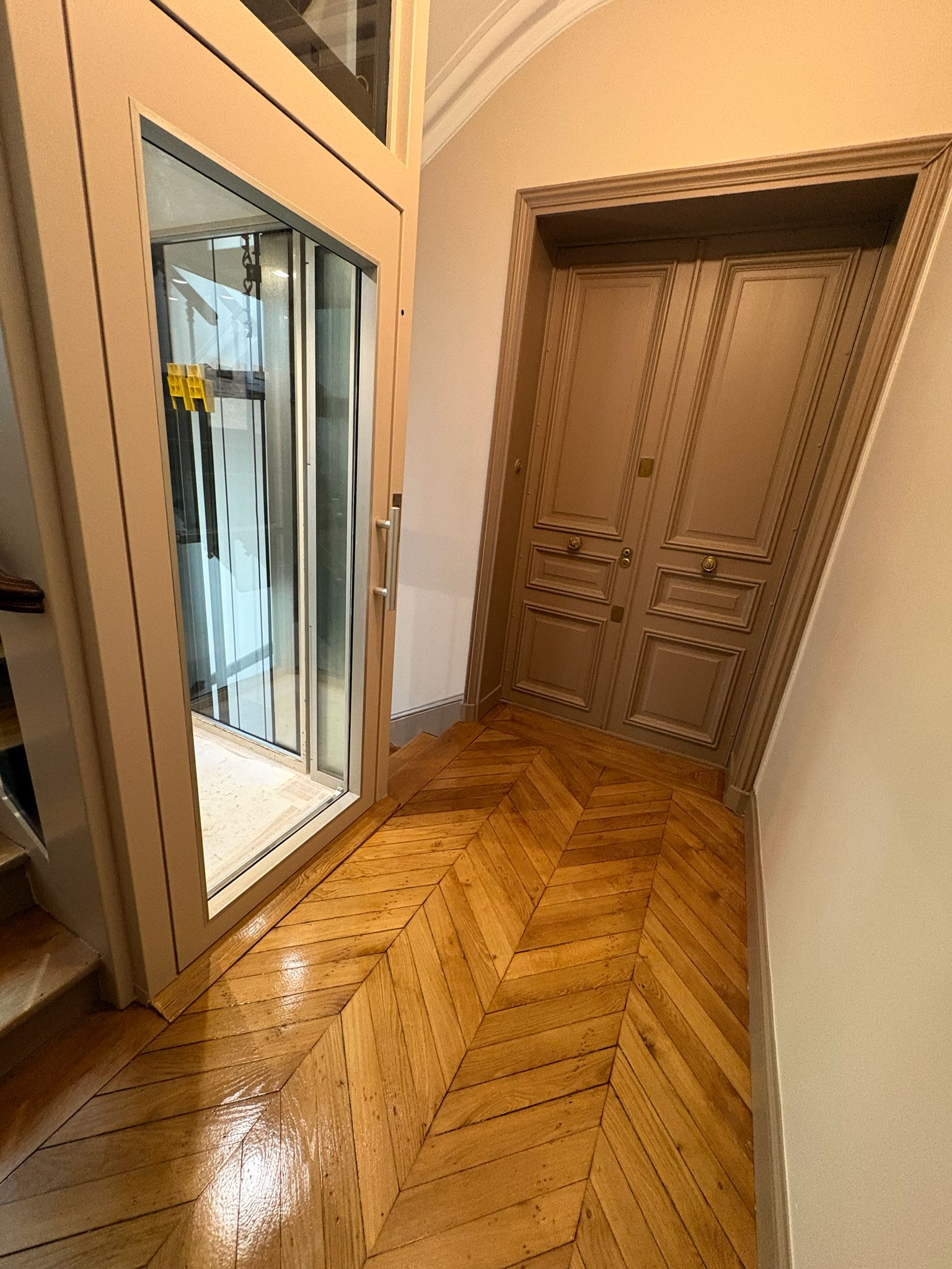 Palier de copropriété après pose du parquet autour de l'ascenseur vitré