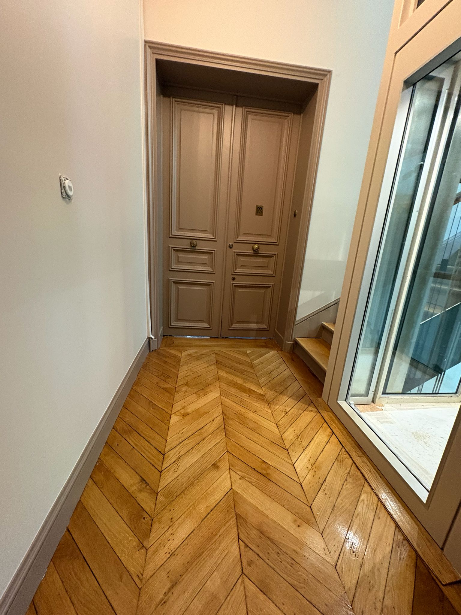 Palier de copropriété après rénovation avec porte palière et parquet