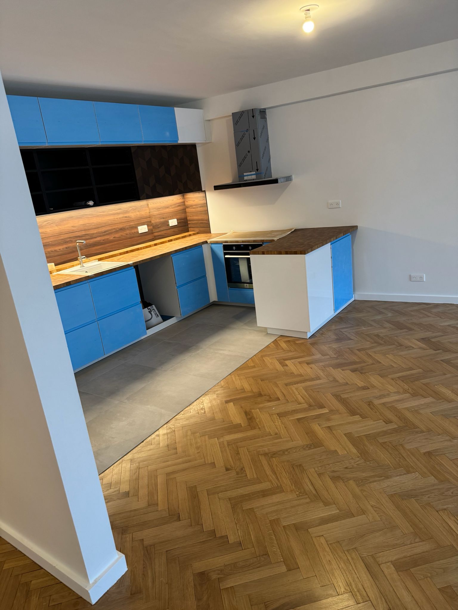 Cuisine créée dans un espace vide avec implantation en L et plan de travail bois